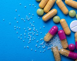 Top view with white pills and yellow capsules and purple and green pills. Copy space and macro
